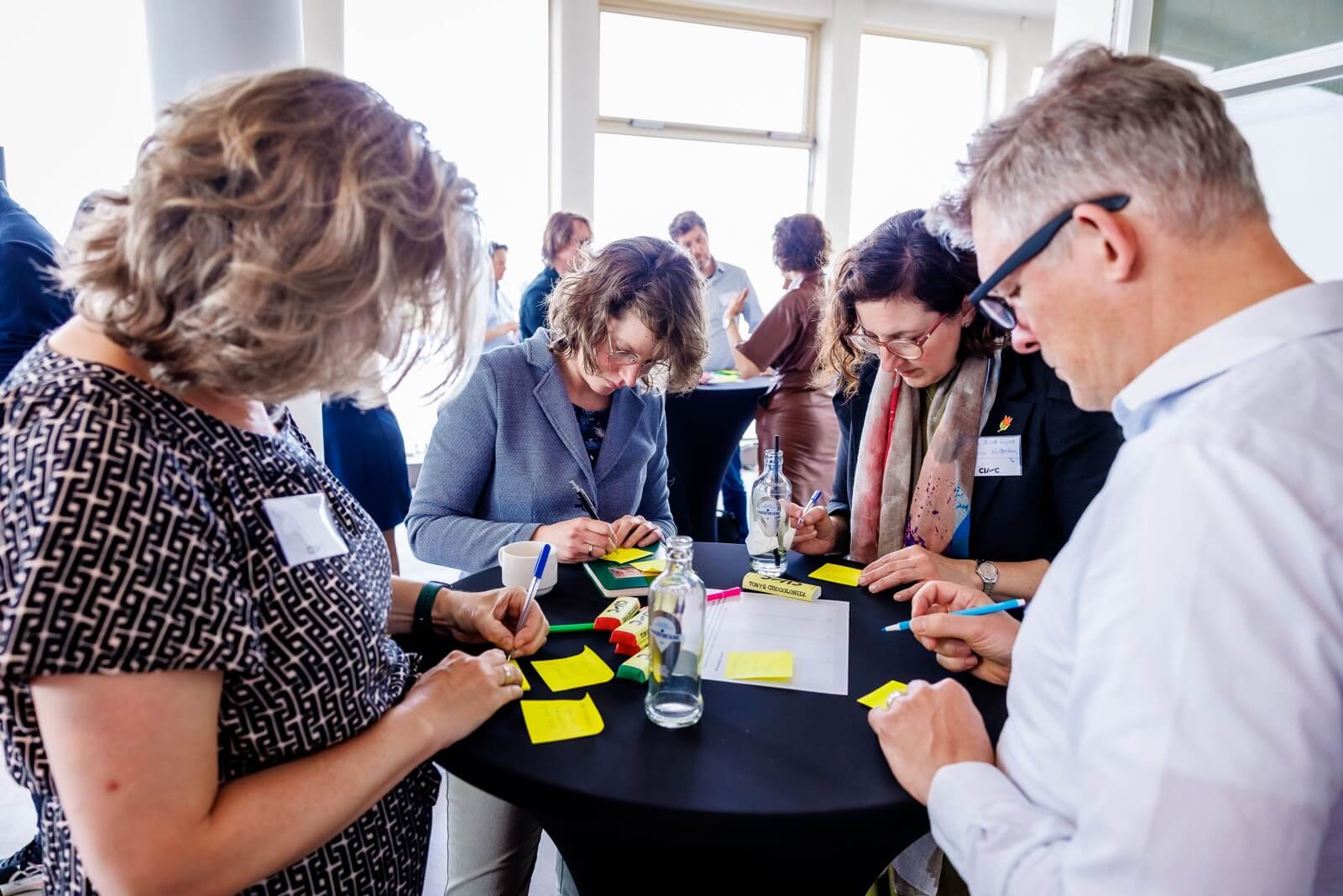 Four people writing on sticky notes at a round table during the CIIIC Annual Meet-up event.